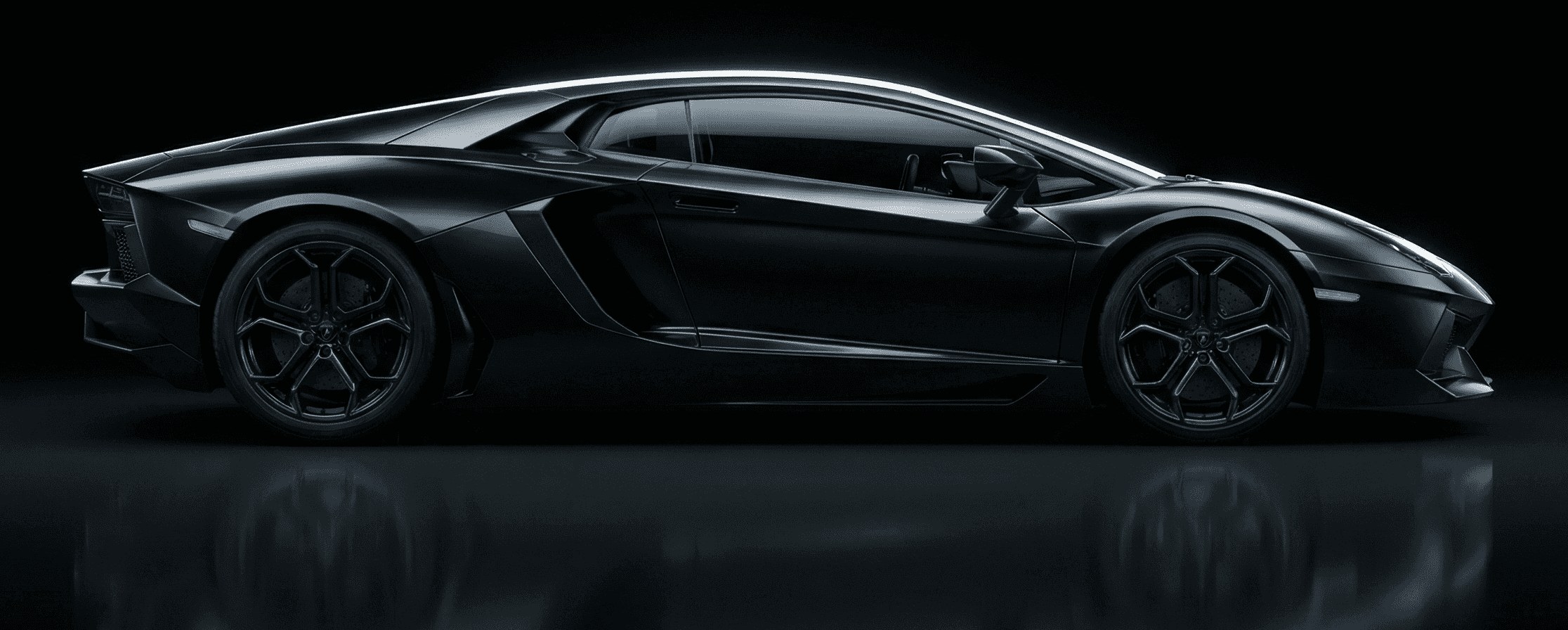 Black Lamborghini Aventador exotic supercar in side profile, studio-lit on a dark reflective floor